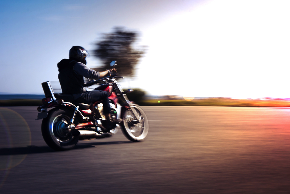 Un motard roulant face au couché de soleil